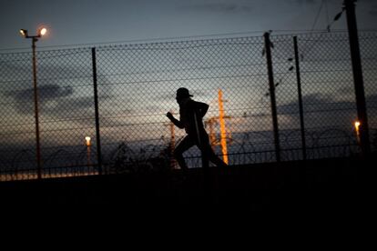 Un inmigrante corre en Calais, al norte de Francia, tras cruzar una verja para intentar acceder al túnel del Canal de La Mancha y llegar a Reino Unido.