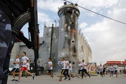 Un grupo de participantes corre a lo largo de la barrera de separación de Israel, que divide Cisjordania desde Jerusalén,en el pueblo de Belén durante el quinto maratón palestino.