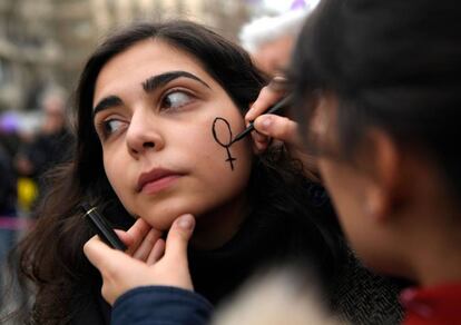 Una mujer pinta otra el símbolo de Venus en la mejilla durante la manifestación de Barcelona.