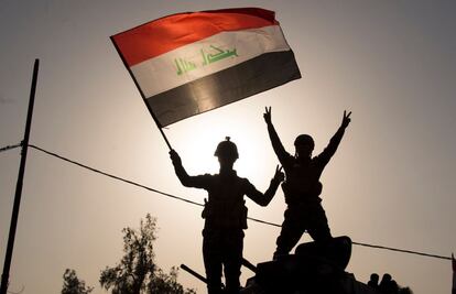 Policías hondean la bandera nacional iraquí, tras la liberación de la ciudad de Mosul, en Irak.