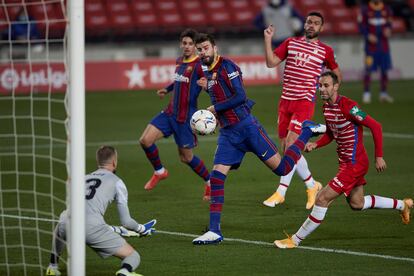 El defensa del Barcelona Gerard Piqué remata un balón ante el portero Aarón Escandell, del Granada.