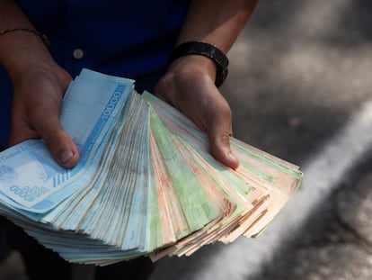 Um trabalhador dos transportes mostra um maço de bolívares, em 12 de março de 2021, em Caracas, quando uma bengala de pão custava um milhão de bolívares.