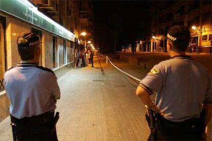 Dos agentes de la Policía Local de Córdoba vigilan en la noche del viernes una calle precintada para evitar el <i>botellón</i>.