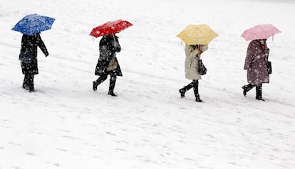 Cuatro personas caminan, protegidos con paraguas, los jardines de las Tullerías, totalmente nevadas.