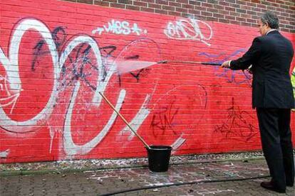 Tony Blair borra pintadas ayer durante una visita al barrio de Swindon, en el sur de Londres.