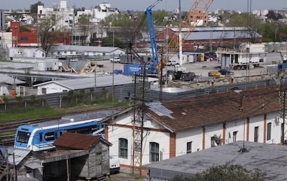 Un servicio del tren Sarmiento pasa por delante del obrador del soterramiento, en Haedo.