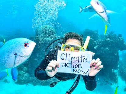Mientras bucea, la activista Sandra Guzmán sostiene un cartel con la frase "Acción climática ya".