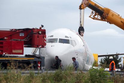 Varios operarios de los servicios de emergencias trabajan para mover el avión de la carretera, en el Aeropuerto de Bérgamo (Italia)