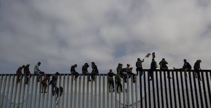 La gente se sienta en la valla fronteriza en Tijuana, en abril.