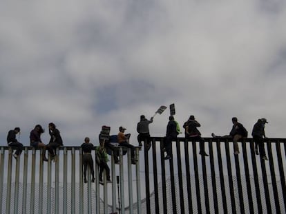La gente se sienta en la valla fronteriza en Tijuana, en abril.