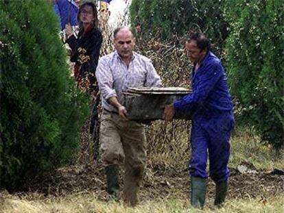 Dos hombres portan una caja de cinc con los restos de Diego Colón. PLANO GENERAL - ESCENA