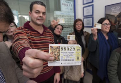 Varios agraciados con el segundo premio del Sorteo del Niño, el 95.379, muestran un décimo de los cien que ha vendido la administración de loterias número 1 de Calasparra (Murcia)