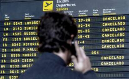 Un hombre habla por el móvil mientras contempa el panel informativo de Salidas del aeropuerto de Manises, Valencia. EFE/Archivo