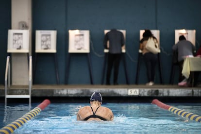 Sarah Salemn, de 34 años, nada mientras los electores depositan su voto en la mesa electoral instalada en la piscina de Echo Deep, en Los Ángeles.