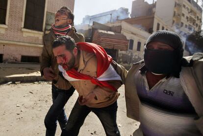 Manifestantes ayudan a un herido durante los enfrentamientos con la policía en los alrededores del Ministerio del Interior, en El Cairo.