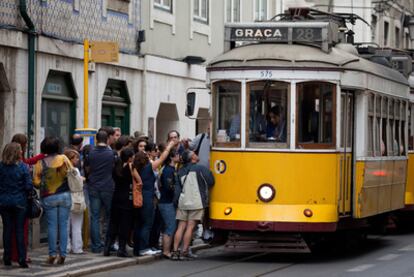 Un grupo de viajeros se agolpa para tomar el tranvía en una calle de Lisboa.