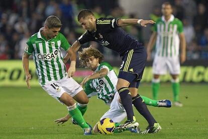 El delantero francés del Real Madrid, Karim Benzema intenta marcharse de los centrocampistas del Betis, Salva Sevilla y Cañas.