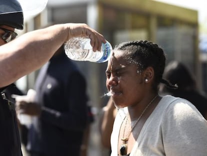 Um policial lava o rosto de uma mulher atingida por spray de pimenta ontem em Baltimore.