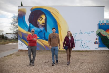 La familia de Ana Isabel García Llorente (Gata Cattana) frente a un mural de su hija en Adamuz, Córdoba, el 8 de febrero. De izquierda a derecha: Andrés (el padre), Antonio (el hermano) y Ana (la madre).