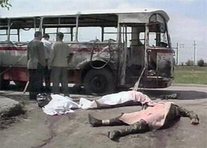 Las fuerzas de seguridad observan el estado en el que ha quedado el autobús mientras dos cuerpos yacen en el suelo.