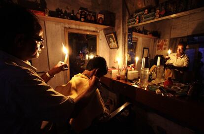 Un barbero indio trabaja con la ayuda de una vela durante el apagón en Calcuta.