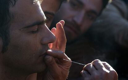 Un migrante cose los labios de un camarada iraní como acto de protesta contra las restricciones impuestas por los países balcánicos para el paso de migrantes, cerca de Gevegelija (Macedonia).