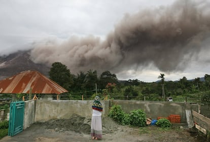 Muchos de los habitantes de la zona se niegan a abandonar sus casas a pesar de las advertencias de que está prevista una poderosa erupción. En la imagen, una mujer observa la nube de flujos piroclásticos del volcán, en Tiga Serngkai, al norte de Sumatra, Indonesia.