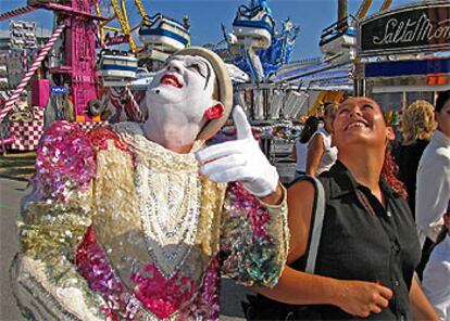 Un payaso del circo señala la noria a los primeros visitantes durante la puesta en funcionamiento de las atracciones de Bilbao.