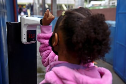 Uma aluna tem sua temperatura medida ao entrar na escola no primeiro dia de aula, em São Paulo.