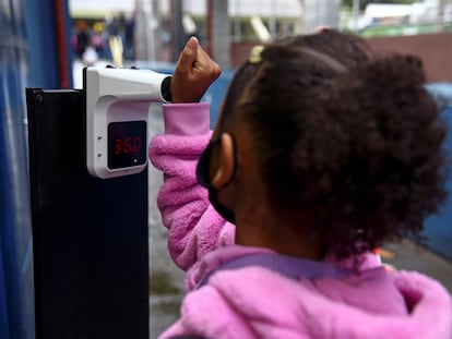 Uma aluna tem sua temperatura medida ao entrar na escola no primeiro dia de aula, em São Paulo.