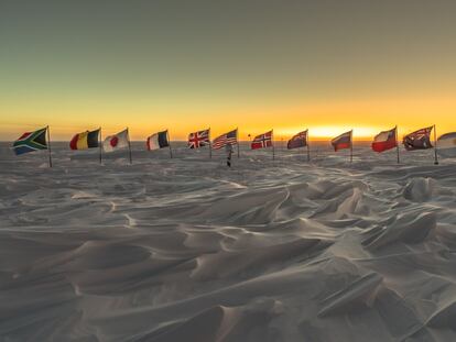 Banderas de los primeros países signatarios del Tratado Antártico tras el marcador del Polo Sur ceremonial, a unos metros del geográfico.