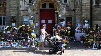 Una mujer con su beb&eacute; pasa este domingo junto a una zona de homenaje a las v&iacute;ctimas del incendio de la torre Grenfell, en North Kensington.