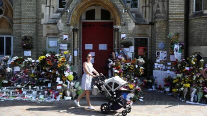 Una mujer con su beb&eacute; pasa este domingo junto a una zona de homenaje a las v&iacute;ctimas del incendio de la torre Grenfell, en North Kensington.