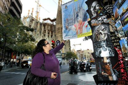 Una mujer observa un cartel con la imagen de Benedicto XVI frente a la Sagrada Familia.