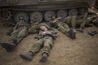 Israeli soldier sleep beside a military vehicle near the Israel Gaza Border, early Tuesday, July 15, 2014. The Israeli Cabinet has accepted an Egyptian proposal for a cease-fire to end a week of conflict with Hamas militants in the Gaza Strip that has killed 185 Palestinians and exposed millions of Israelis to Hamas rocket fire. No Israelis have been killed as a result of Hamas rocket launches. A senior Hamas official says the Palestinian militant group rejects an Egyptian proposal for a cease-fire with Israel. (AP Photo/Ariel Schalit)
