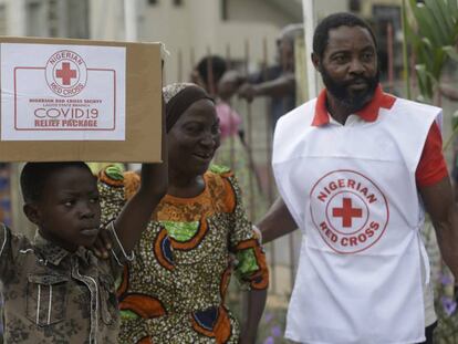 Un niño y su madre en el suburbio de Makoko, en Lagos, transportan una caja con comida que han recibido de la Cruz Roja nigeriana el domingo 25 de abril de 2020.