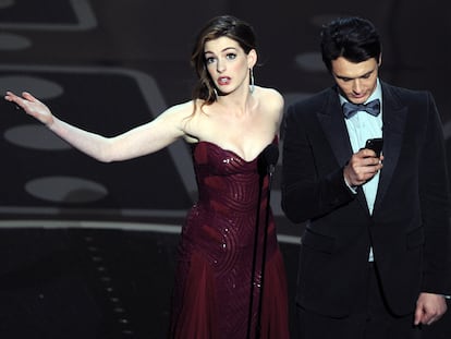 Anne Hathaway mirando al público y James Franco mirando al móvil mientras presentaban la gala de los Premios Oscar del año 2011, una de las que peores críticas ha recibido en los últimos años.