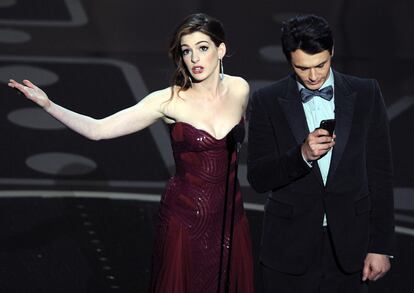 Anne Hathaway mirando al público y James Franco mirando al móvil mientras presentaban la gala de los Premios Oscar del año 2011, una de las que peores críticas ha recibido en los últimos años.