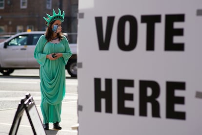 Una mujer disfrazada de estatua de la Libertad espera para votar a primera hora de la mañana en la puerta de un colegio electoral en Hoboken, New Jersey.