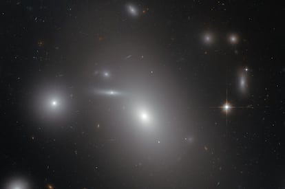 La galaxia elíptica NGC 4889, el objeto más brillante en el centro de la imagen, oculta un descomunal agujero negro en su interior