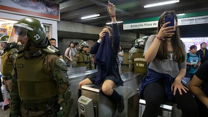 Carabineros de Chile junto a estudiantes que bloquean el torniquete del metro en protesta por el aumento del costo del pasaje, en Santiago, el 18 de octubre de 2019.