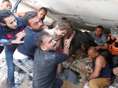 Agentes de resgate carregam menina em meio a buscas por sobreviventes após bombardeio de Israel.