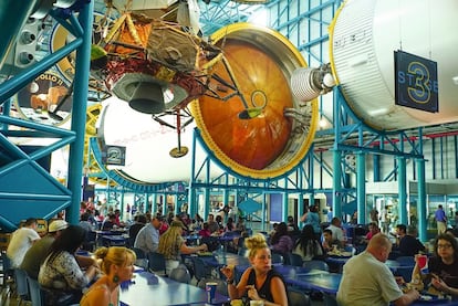 Hora del almuerzo para los turistas, bajo el cohete Saturn V.