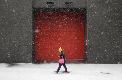 Una mujer camina bajo la nevada por una calle de Baltimore.