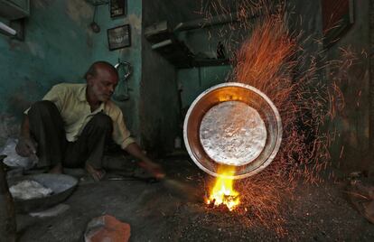 Un trabajador forja una cazuela de cocina en el interior de su taller, en la ciudad india de Ahmedabad.
