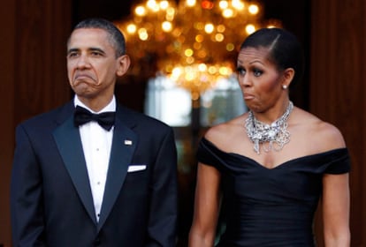 El presidente Obama y la primera dama Michelle gesticulan ante la llegada del coche que traslada a la reina Isabel II y el duque de Edimburgo.