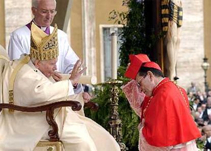 El nuevo cardenal español Julián Herranz se coloca el birrete ante el Papa.