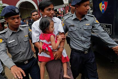 El periodista detenido de Reuters, Kyaw Soe Oo, sostiene a su hija en brazos mientras es escoltado por un oficial de policía hacia el Tribunal de Insein en Yangon (Myanmar).