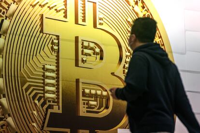 A pedestrian walks past an advertisement for the Bitcoin cryptocurrency.