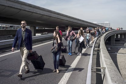 Viajeros caminan por una autopista hacia el aeropuerto Charles de Gaulle, de París, tras quedar sus vehículos atrapados por las protestas de taxistas contra Uber.